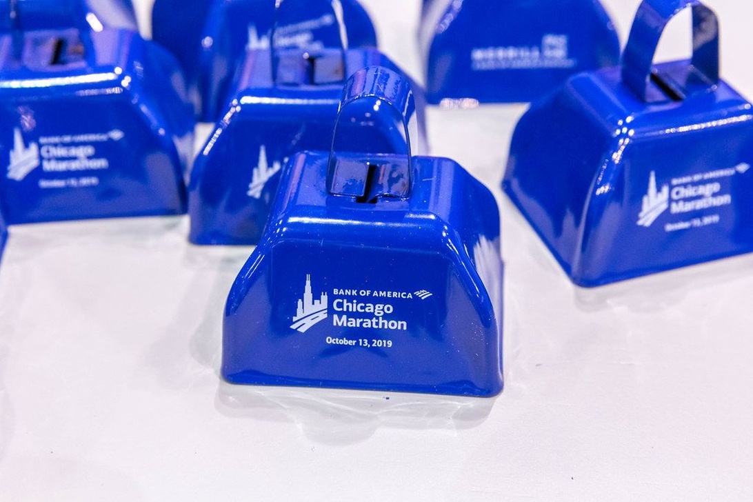 En samling klarblåa, specialdesignade supporterbjällror med Bank of America Chicago Marathon-logotypen från 2019, som visar hur anpassade giveaways kan se ut för ett stort event.
